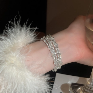 Dettaglio del bracciale elastico a tre strati di strass con perle finte sul polso