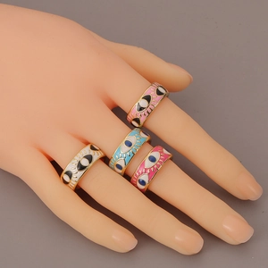 Set of four colorful enamel evil eye rings in gold finish worn by a model hand
