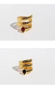 Detailed view of layered gold snake rings featuring red and black teardrop zircons