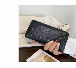 Detail einer schwarzen Lederclutch mit silbernen Nietentexturen und goldenem Reißverschluss