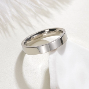 Polished silver stainless steel band ring displayed on white minimalist props