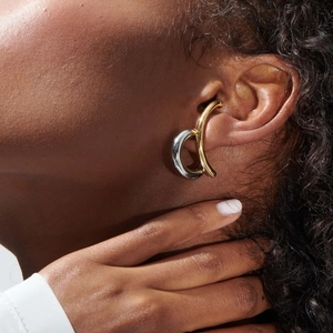 Close-up of bicolor gold and silver ear cuff in irregular shape worn by model