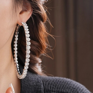 Close-up of a large silver hoop earring with sparkling rhinestones on model's ear