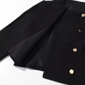Dettaglio dei bottoni dorati vintage e della fodera nera sulla giacca da tailleur