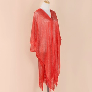 Detail of red hollow knit shawl featuring shimmering metallic yarn and long fringe tassels