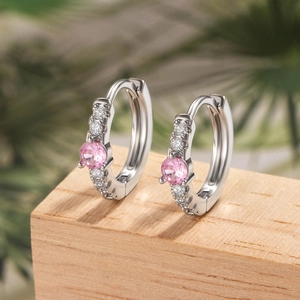 Silver drop earrings with pink round zircon and clear crystals on a natural green background