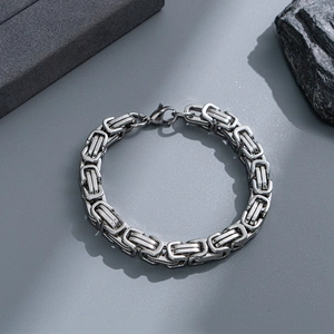Detailed close-up of a silver Byzantine chain bracelet with a lobster clasp on a stone base