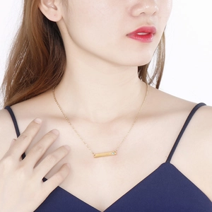 Minimalist gold horizontal bar necklace with a blue birthstone pendant on a model