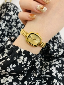 Close-up of a gold square dial watch with diamond markers on a woman's wrist