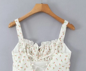 Detail of white floral camisole with red roses, ruffled neckline and back lace-up design