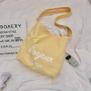 Dettaglio della borsa tote in tela gialla con stampa Bonjour magic e tracolla a righe