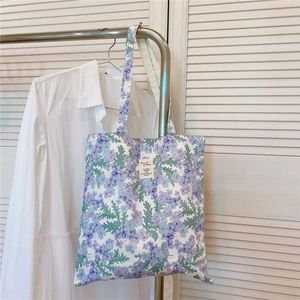 Gros plan d'un sac cabas en toile à motif floral violet suspendu à un cintre
