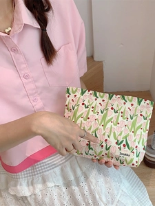 Floral tulip canvas makeup bag in cream white shown held in hand by a model