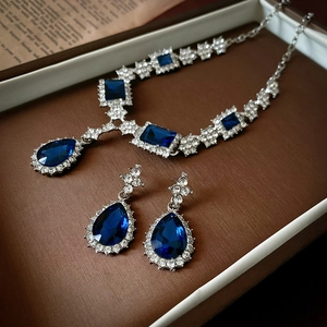 Detailed close-up of dark blue teardrop jewelry set with necklace and earrings in a gift box