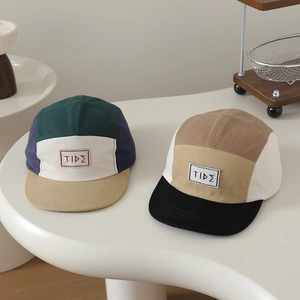 Cappellini 5-panel color block per bambini con patch TIDE su superficie bianca