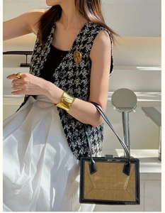 Detail of wide polished gold metal cuff bracelet paired with elegant tweed vest outfit