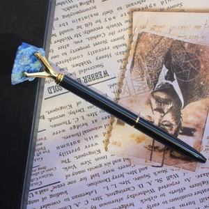 Détail d'un stylo vintage noir avec griffes dorées tenant une pierre de lapis-lazuli