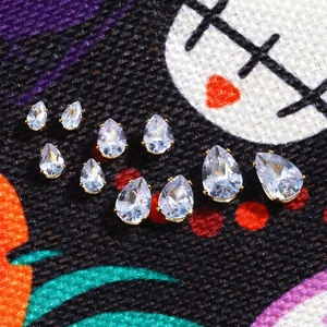 Macro view of 6-12mm pear cut teardrop zircons in gold settings spread on fabric