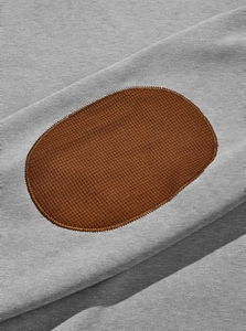 Détail du patch coude marron et du tissu tricoté gris sur un sweat à capuche pour hommes