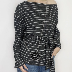 Detail of a mini heart-shaped rhinestone crossbody bag paired with a striped long sleeve top