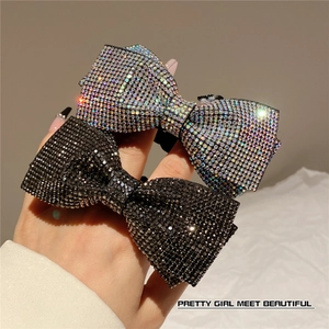 Detail of handcrafted rhinestone bow hair clips in black and iridescent silver finishes