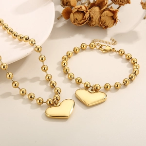 Detailed set of gold beaded chain necklace and bracelet with polished heart pendants