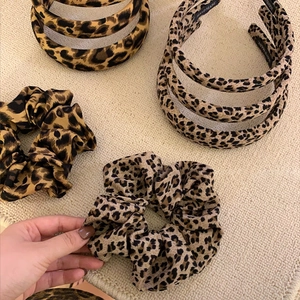 Vintage leopard print scrunchies and headbands on textured linen background