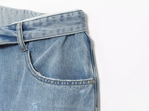 Dettaglio macro della vita dei jeans azzurri con cuciture e rivetti in metallo
