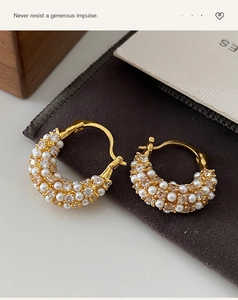 Macro detail of gold plated hoop earrings featuring sparkling zircons and white pearls