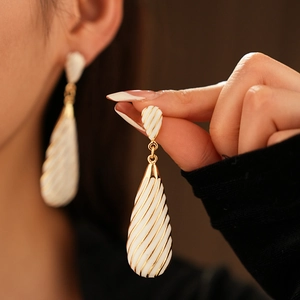 Détail de boucles d'oreilles vintage en émail blanc avec motifs rayés dorés