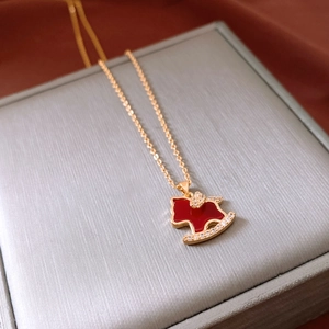 Macro view of a gold plated rocking horse necklace with red details and crystals