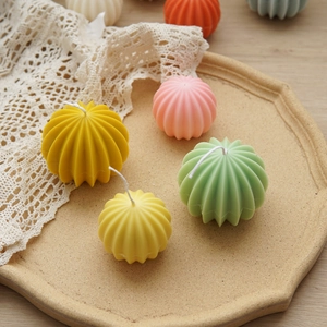 Detailed top view of colorful sphere candles with vertical stripes on a ceramic tray