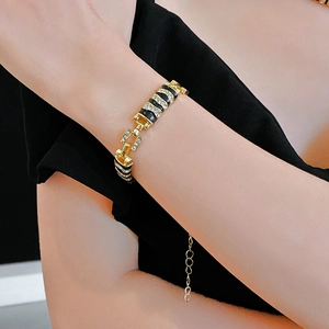 Detail view of gold-toned bracelet with black enamel and sparkling rhinestones on wrist