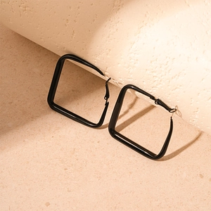 Detail shot of large black square hoop earrings with a glossy minimalist finish