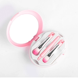 Close-up of portable pink makeup brush travel set with round mirror and 3 soft brushes