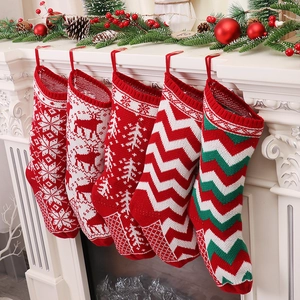 Five knitted Christmas stockings with snowflake and reindeer patterns on a fireplace