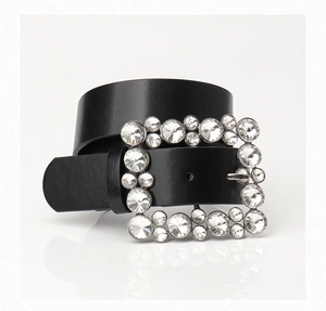 Close-up of black leather belt featuring a large square buckle encrusted with clear rhinestones