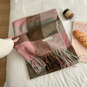 Plaid tassel scarf in pink and brown tones on a white bed with aesthetic props
