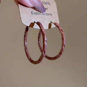Detail of dusty rose hammered texture hoop earrings with a vintage geometric design