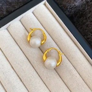 Elegant gold-plated round hoop earrings with large white pearls on beige velvet jewelry box
