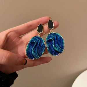 Close-up of vintage resin earrings with blue oval pendants and golden metallic edges