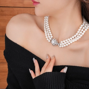 Close-up of triple-layer pearl necklace featuring a sparkling diamond-set flower clasp