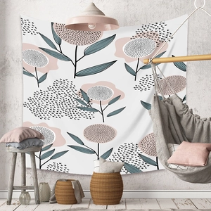Detail of bohemian tapestry featuring pink floral patterns on a textured white wall