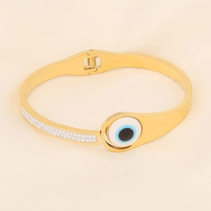 Detail of golden evil eye bracelet with sparkling double-row rhinestones and silk backdrop