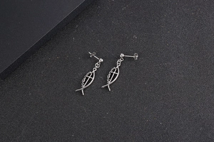 Detailed view of silver titanium steel fish-shaped earrings with cross on black texture