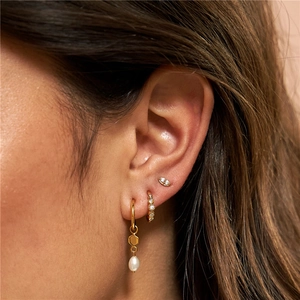 Detailed close-up of gold flower earrings set with pearls and marquise cut diamonds