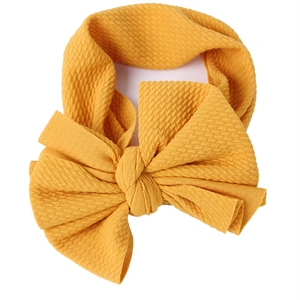 Elastic baby headband in ginger yellow waffle knit fabric with a large bow decoration