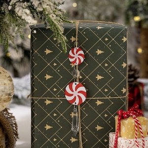 Detail of red and white candy ornaments hanging on a green gift box with festive lights