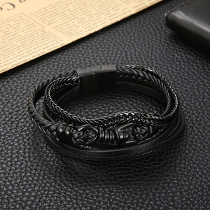 Detail of black woven leather layers with metallic magnetic clasp on a textured surface