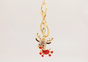Close-up of a gold metal reindeer keychain with clear and red rhinestone inlay details